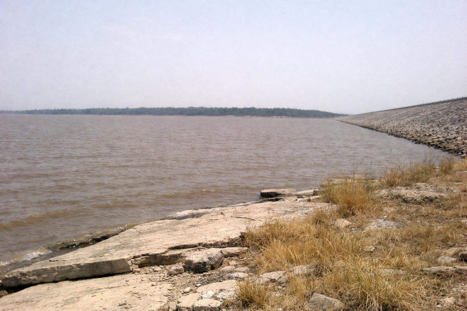 The shore of a large reservoir under a wide sky