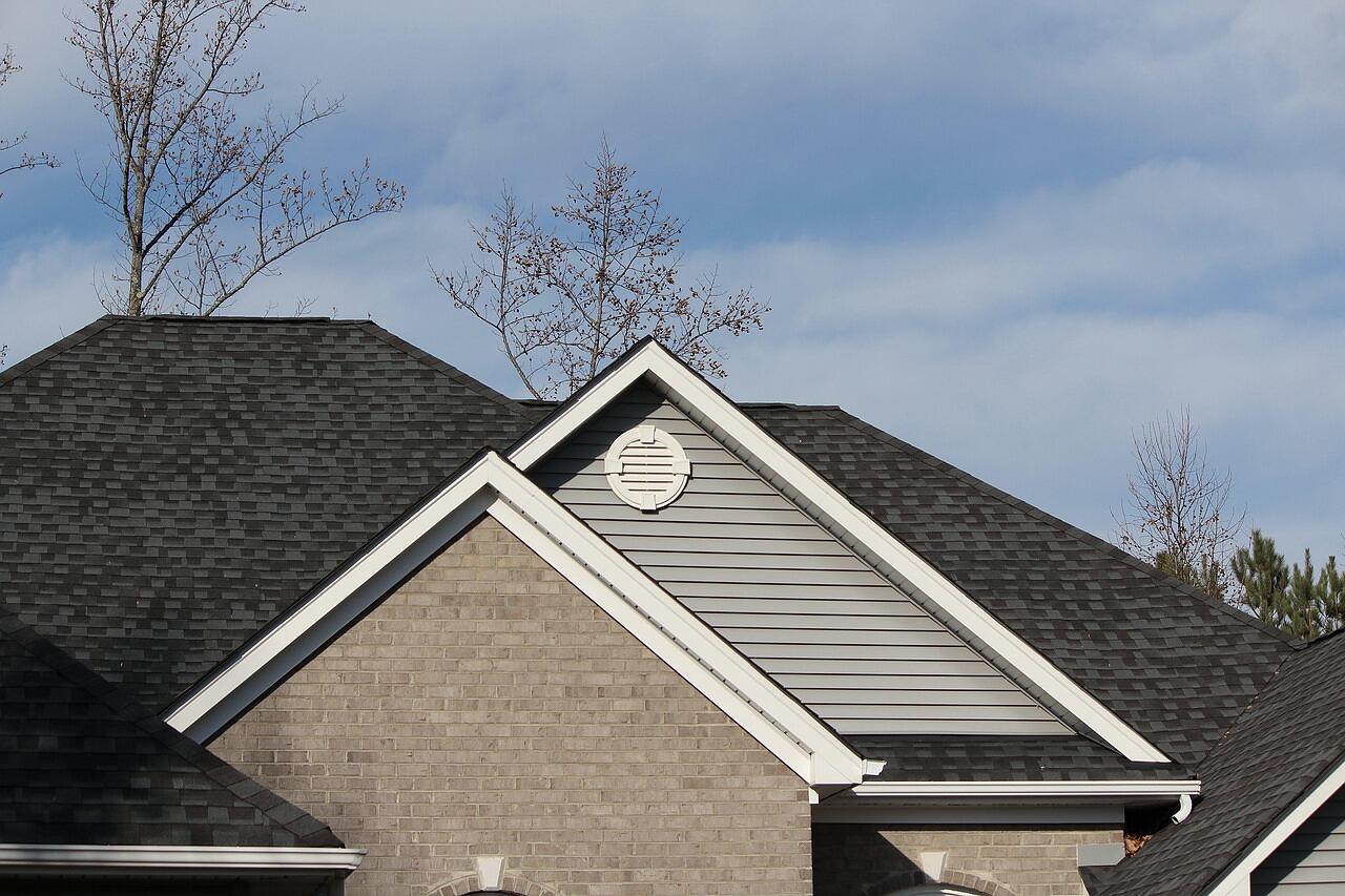 The eave of a house showing the soffit, fascia and a roof vent against the sky