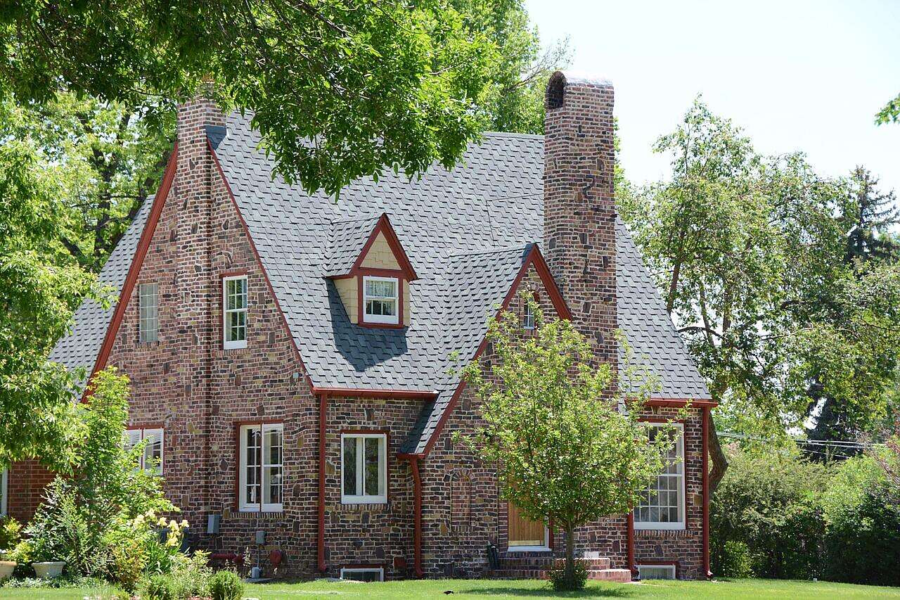 A 1920s Tudor revival house with a steep roof and mature trees