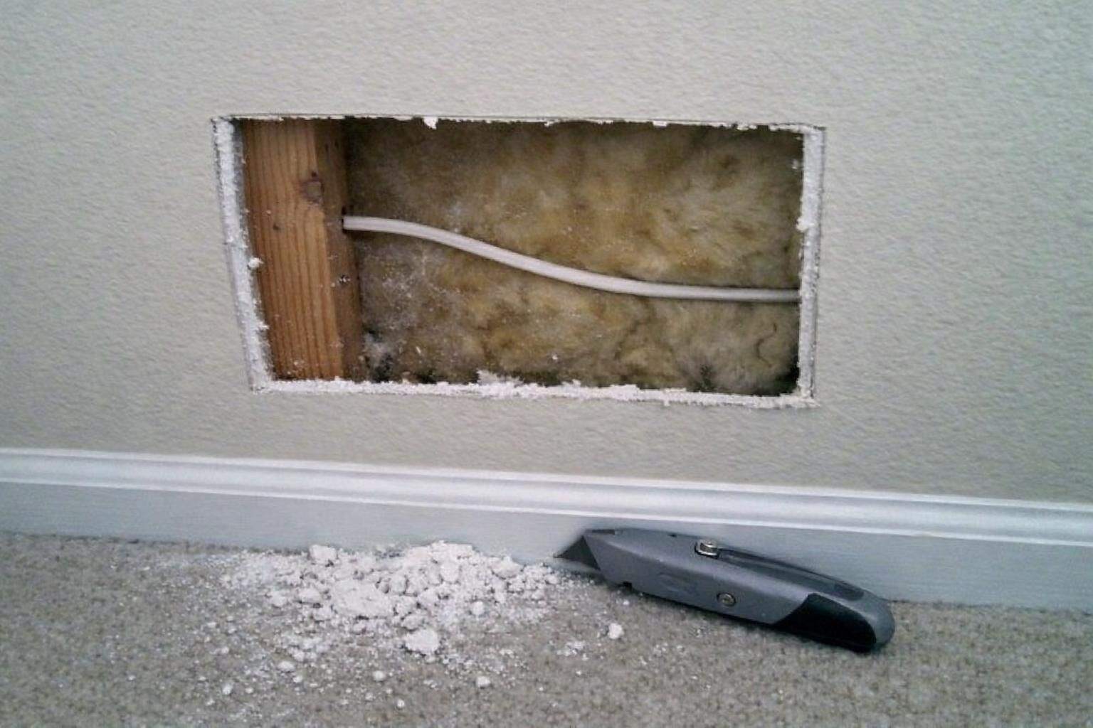 An opening cut into drywall exposing the stud bay behind it